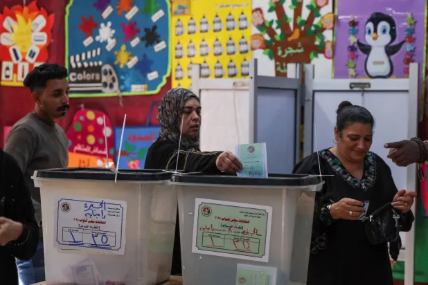 سيدة تضع البطاقة الانتخابية في صندوق الاقتراع بإحدى لجان التصويت لانتخابات مجلس النواب بمحافظة الجيزة (رويترز)