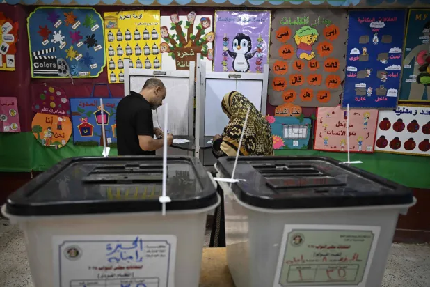 Voters mark their ballots at a polling station in Giza, the twin city of Cairo, during the parliamentary elections on November 10, 2025. (AFP)