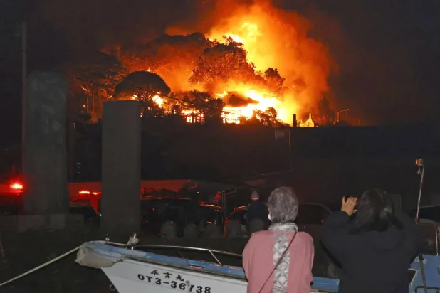Residents watch flames rise from the site of a fire in Oita, southern Japan Tuesday, Nov. 18, 2025. (Kyodo News via AP)