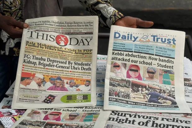 بائع صحف في لاغوس يعرض صحفاً تتصدر صفحاتها الأولى عملية خطف تلميذات من مدرسة داخلية ثانوية بمنطقة كيبي في نيجيريا يوم الاثنين الماضي (أ.ب)