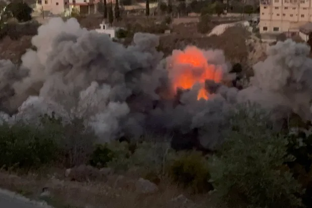 النيران تندلع والدخان يتصاعد من منزل استهدفته غارة إسرائيلية في بلدة طيرفلسيه بجنوب لبنان بعد إنذار بالإخلاء (رويترز)