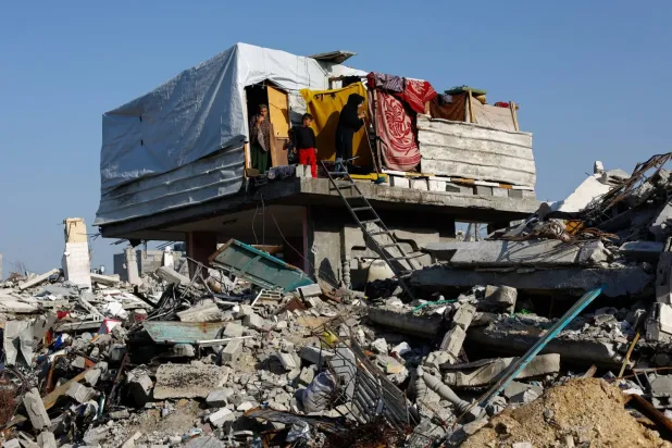 Filistinliler Gazze'nin kuzeyindeki bir evin yıkıntıları üzerinde duruyor (Reuters)