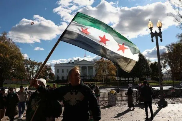 A Syrian flag is held aloft outside the White House following the meeting of US President Donald Trump and Syrian President Ahmed al-Sharaa in the Oval Office of the White House in Washington, D.C., US, November 10, 2025. REUTERS/Kevin Lamarque

