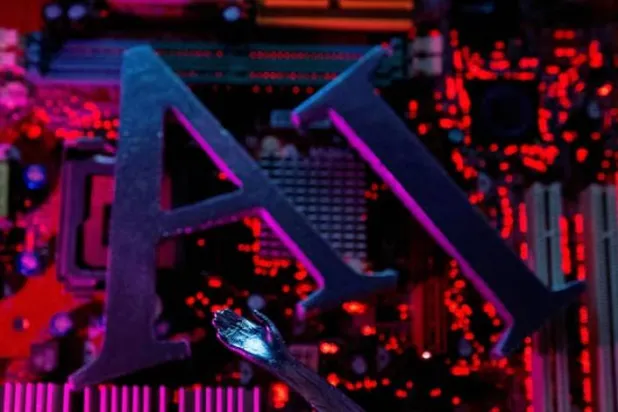 حروف «إيه آي» (الذكاء الاصطناعي) مع يدٍ آلية موضوعة فوق لوحة أمّ للكمبيوتر في هذه الصورة التوضيحية (رويترز)