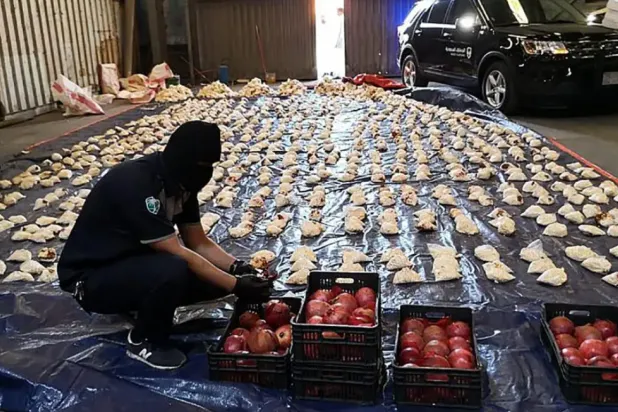 FILE - In this Friday, April 23, 2021 file photo, released by Saudi Press Agency, a Saudi custom officer opens imported pomegranates, as customs foiled an attempt to smuggle over 5 million pills of an amphetamine drug known as Captagon, which they said came from Lebanon, at Jiddah Islamic Port, Saudi Arabia.  (Saudi Press Agency via AP, File)

