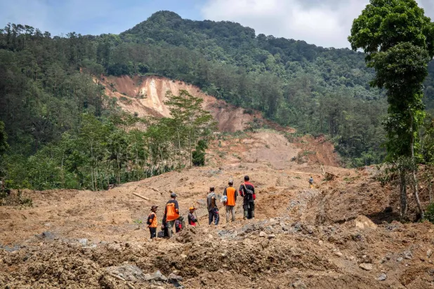 Rescue volunteers stand at the site of a landslide in Situkung village, Banjarnegara, Central Java, on November 18, 2025. (Photo by DEVI RAHMAN / AFP)