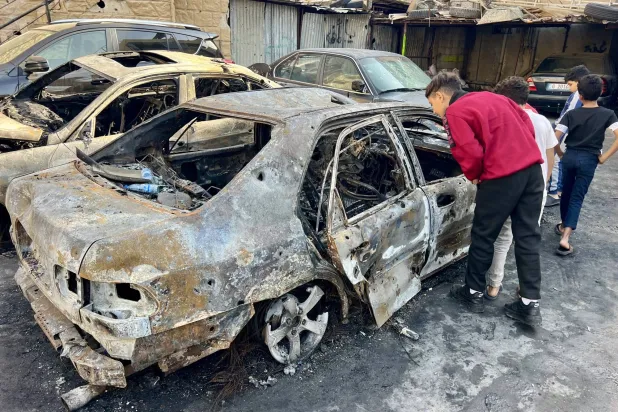 People inspect a burnt car at an Israeli airstrike site in the Palestinian refugee camp Ain al-Hilweh near the port city of Sidon, southern Lebanon, 20 November 2025. (EPA)