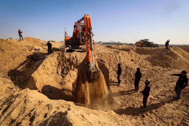 Masked gunmen belonging to the Islamic Jihad movement stand next to an earth mover bearing an Egyptian flag, while searching for the bodies in Nuseirat refugee camp in the central Gaza Strip, on November 21, 2025. (AFP)
