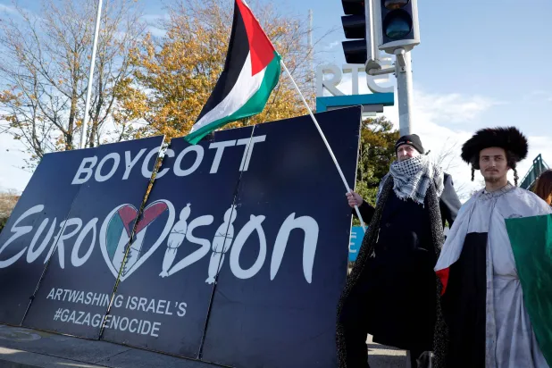 Pro-Palestinian protestors hold a flag and a banner outside the RTE (Radio Telefis Eireann) Irish public service broadcaster television studios as demonstrators call for an Irish boycott of the 2026 Eurovision Song Contest if there is Israeli participation, in Dublin, Ireland, November 1, 2025. (Reuters)