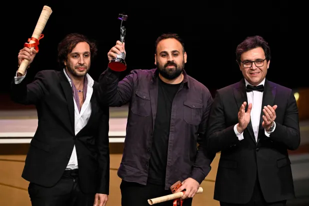 عامر ناصر (يسار) يتسلم جائزة مهرجان القاهرة السينمائي الدولي لفيلم «كان يا ما كان في غزة» نيابة عن المخرجين طرزان وعرب ناصر (أ.ف.ب)