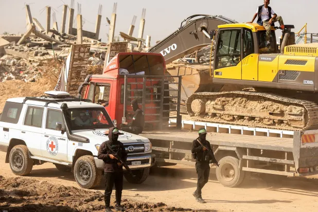 مسلحون من «حماس» يرافقون أعضاء الصليب الأحمر نحو منطقة داخل ما يسمى «الخط الأصفر» الذي انسحبت إليه القوات الإسرائيلية بموجب وقف إطلاق النار (رويترز)