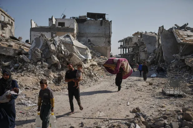 فلسطينيون يسيرون وسط دمار في جباليا بقطاع غزة (أ.ب)