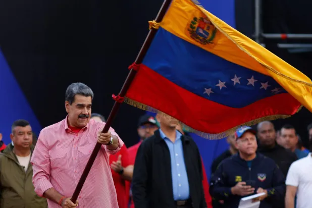 Venezuela's President Nicolas Maduro waves a Venezuelan flag during a demonstration for the swearing-in of Bolivarian committees in Caracas on November 15, 2025. (Photo by AFP)