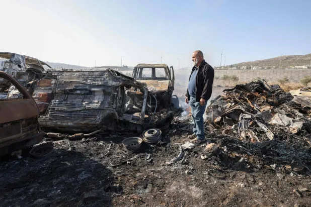 A Palestinian man Ahmad Dalal, 57, inspects scrap cars burnt in an attack by Israeli settlers, in Huwara in the Israeli-occupied West Bank, November 21, 2025.  (Photo by JAAFAR ASHTIYEH / AFP)