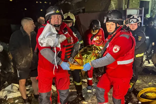 Rus hava saldırılarının Harkiv'i hedef almasının ardından sağlık görevlileri bir kurbanın cesedini taşıyor (Reuters)