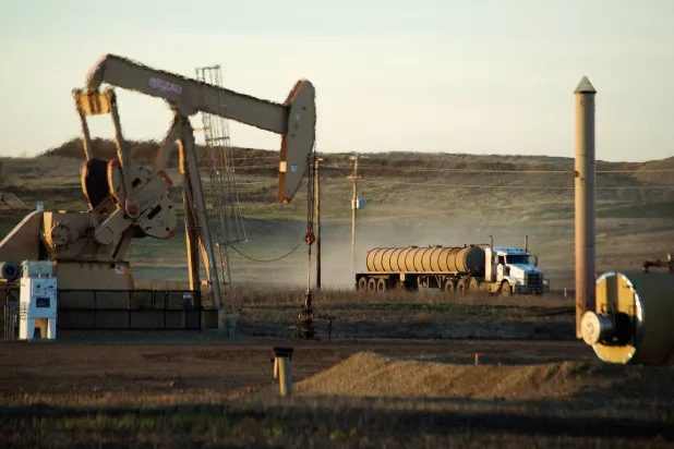 FILE PHOTO: A service truck drives past an oil well on the Fort Berthold Indian Reservation in North Dakota, November 1, 2014.  REUTERS/Andrew Cullen/File Photo