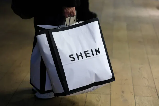 FILE PHOTO: A customer holds shopping bags with a Shein logo in the first physical space of Chinese online fast-fashion retailer Shein on the day of its opening inside the Le BHV Marais department store, the Bazar de l'Hotel de Ville, in Paris, France, November 5, 2025. REUTERS/Sarah Meyssonnier/File Photo
