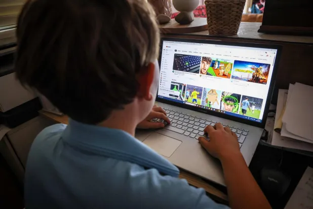 This photo taken on October 24, 2025 shows a fourteen-year-old boy posing at his home near Gosford, Australia as he looks at social media on his computer. (Photo by DAVID GRAY / AFP)