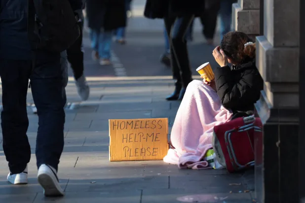 شخص من دون مأوى يتوسل بينما تواجه وزيرة الخزانة البريطانية راشيل ريفز قرارات مالية صعبة (رويترز)