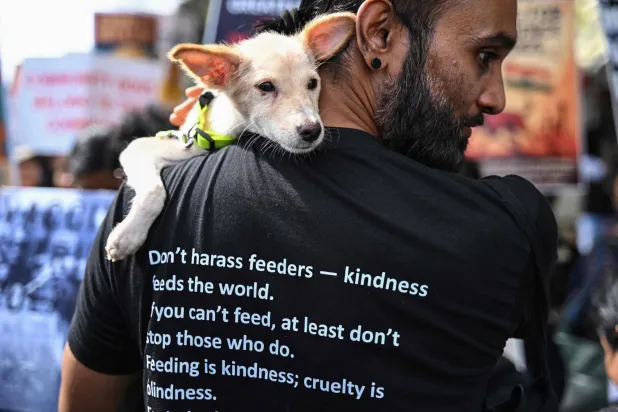 رجل يحمل كلباً على كتفه (أ.ف.ب)