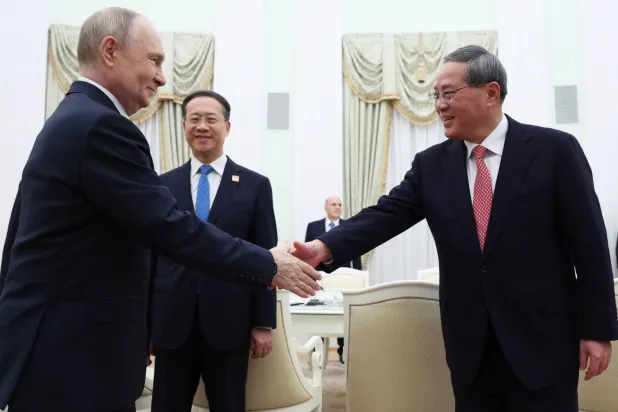 الرئيس الروسي فلاديمير بوتين ورئيس الوزراء الصيني لي تشيانغ يتصافحان خلال اجتماعهما في الكرملين بموسكو (أ.ب)