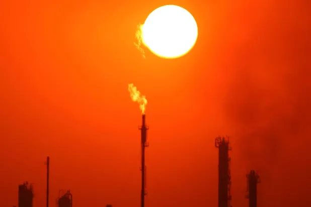 الشمس تغرب خلف مشاعل الغاز المشتعلة في مجمع مصفاة الدورة النفطية في بغداد (أ.ف.ب)