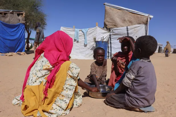 Sudanese refugee children from el-Fasher share a meal from a single plate at the Tine transit refugee camp, amid the conflict between the paramilitary Rapid Support Forces (RSF) and the Sudanese army, in eastern Chad, November 22, 2025. (Reuters)