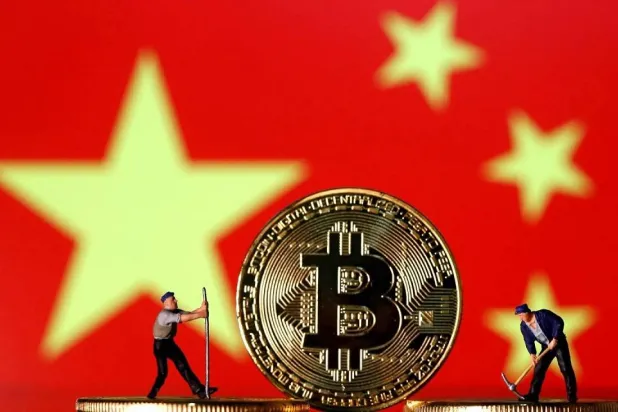 Small toy figurines are seen on representations of the Bitcoin virtual currency displayed in front of an image of China's flag in this illustration picture, April 9, 2019. (Reuters)