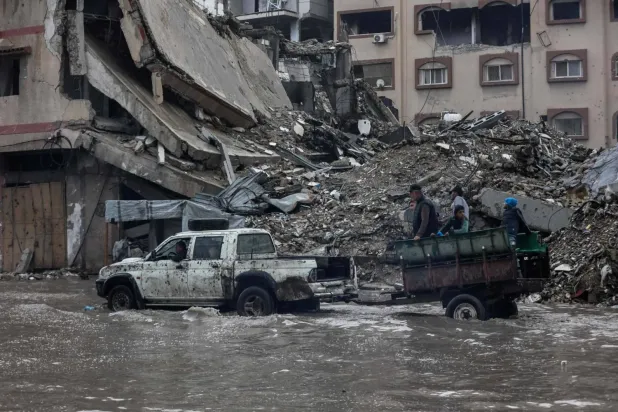 Dün şiddetli yağmurların ardından Gazze şehrindeki bir mülteci kampında, bir araba tarafından çekilen römorkta bulunan Filistinliler (AFP)