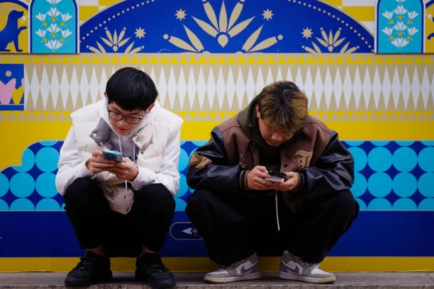 People use their smartphones on a street in Shanghai, China, 20 November 2025. (EPA)