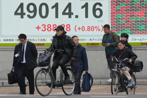 مشاة يمرون أمام شاشة تعرض حركة الأسهم وسط العاصمة اليابانية طوكيو (أ.ب)