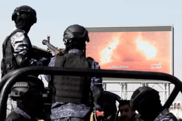 عناصر حوثيون أمام شاشة كبيرة تنقل صوراً لهجمات نفَّذتها الجماعة في البحر الأحمر (غيتي)