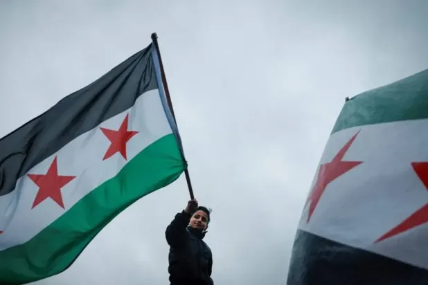 A demonstrator waves the Syrian opposition flag, also known as the revolution flag, during a gathering with other supporters and members of the Syrian community called by the Syria Solidarity Campaign group in Trafalgar Square, central London, on December 8, 2024, to celebrate the fall of the Assad regime. (AFP)

