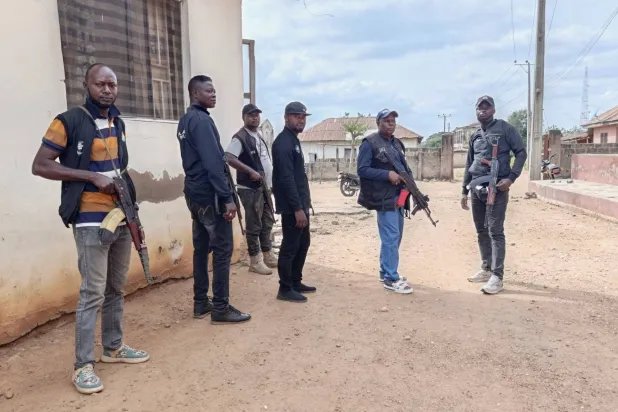 عناصر من الشرطة يحملون أسلحة خارج كنيسة في بلدة إروكو بولاية كوارا النيجيرية (رويترز)