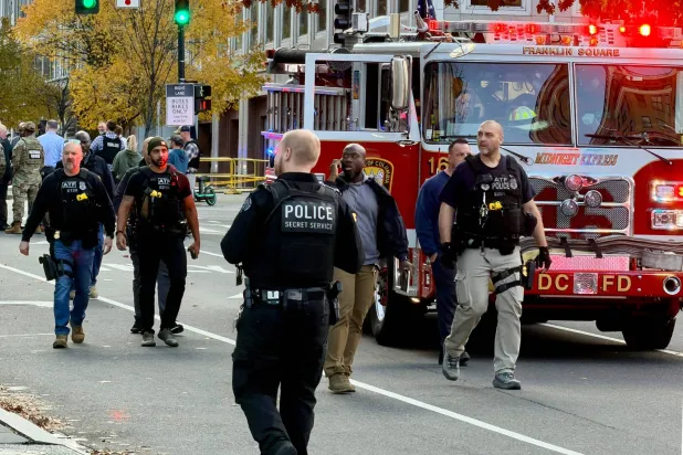 ضباط إنفاذ القانون يسيرون قرب مسرح جريمة بعد إطلاق نار في وسط مدينة واشنطن العاصمة 26 نوفمبر 2025. أُطلق النار على اثنين من أفراد الحرس الوطني الأربعاء على بُعد خطوات قليلة من البيت الأبيض وفقاً لمسؤولين (أ.ف.ب)
