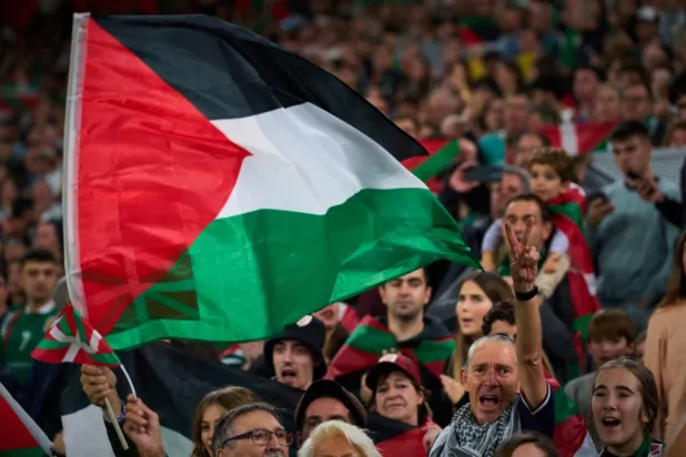 Fans wave Palestinian flags during a friendly match between a selection of Palestinian players and a group of Spanish players from the Basque Country, held to protest Israel’s military actions in Gaza, in Bilbao, Spain, Saturday, Nov. 15, 2025. (AP Photo/Miguel Oses)

