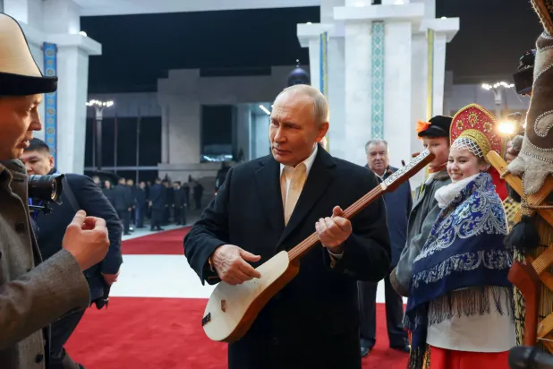 بوتين يحمل آلة موسيقية في بشكيك 27 نوفمبر (إ.ب.أ)