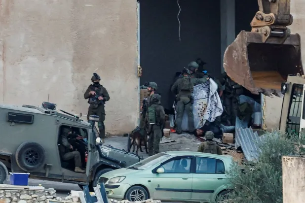 Israeli soldiers hold a blanket to cover the scene of a shooting during a raid in Jenin in the Israeli-occupied West Bank, November 27, 2025. REUTERS/Mohamad Torokman