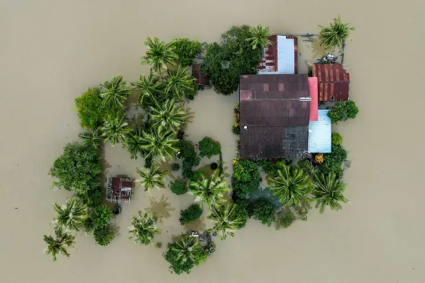 An aerial view shows a home surrounded by flood waters in Kangar in northern Malaysia's Perlis state on November 28, 2025. (Photo by Mohd RASFAN / AFP)