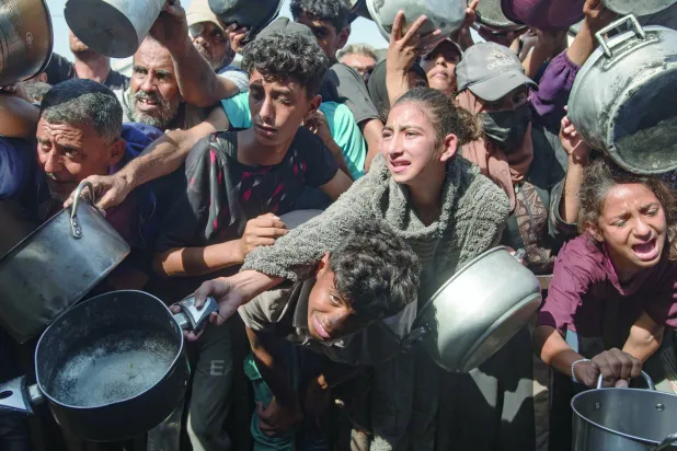 نازحون يحاولون الحصول على وجبة طعام من مطبخ خيري في خان يونس جنوب قطاع غزة يوم 31 أكتوبر 2025 (إ.ب.أ)