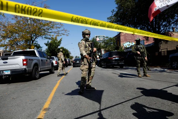 Masked US Customs and Border Protection (CBP) Border Patrol agents stand behind a police line as residents of Chicago's Brighton Park neighborhood confront law enforcement at a gas station after Immigration and Customs Enforcement (ICE) agents allegedly detained an unidentified man riding in his car, in Chicago, Illinois, on October 4, 2025. (Photo by OCTAVIO JONES / AFP)
