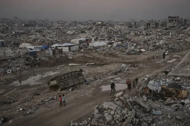  Palestinians walk past a destroyed Israeli armored vehicle amid widespread devastation in Gaza City Thursday, Nov. 27, 2025. (AP) 