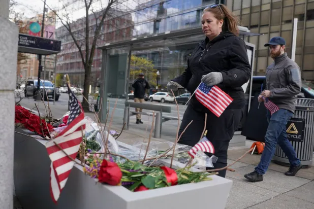 سكان العاصمة واشنطن يحملون الأعلام لنصب تذكاري مؤقت أقيم بالقرب من البيت الأبيض بعد إطلاق النار على اثنين من أفراد الحرس الوطني في واشنطن العاصمة (رويترز)