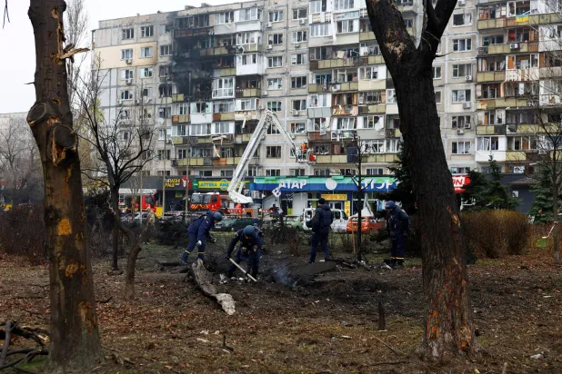 أفراد من خدمات الطوارئ يتفقدون حفرة بالقرب من مبنى سكني في أعقاب هجوم صاروخي روسي على كييف (رويترز)