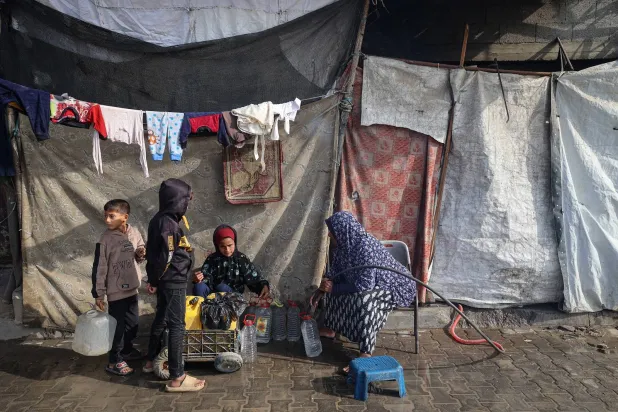 امرأة تملأ حاويات بالمياه في مخيم النصيرات للنازحين الفلسطينيين وسط قطاع غزة (أ.ف.ب)