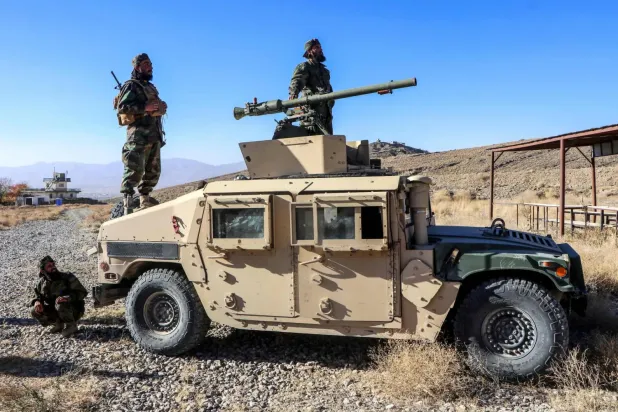 Paktiya vilayetinin Gardez kenti yakınlarındaki 203 Mansuri Kolordusu Eğitim Merkezi’nde düzenlenen mezuniyet töreninde bir askeri aracın üzerinde poz veren Taliban ordusuna yeni katılan askerler, 2 Kasım 2025 (AFP)