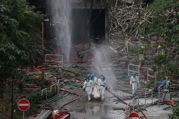 ضباط الشرطة في هونغ كونغ يحملون جثة تم انتشالها من مبنى سكني متضرر بفعل الحريق (رويترز)