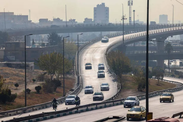Traffic moves in heavy smog in Tehran on November 29, 2025. (Photo by ATTA KENARE / AFP)