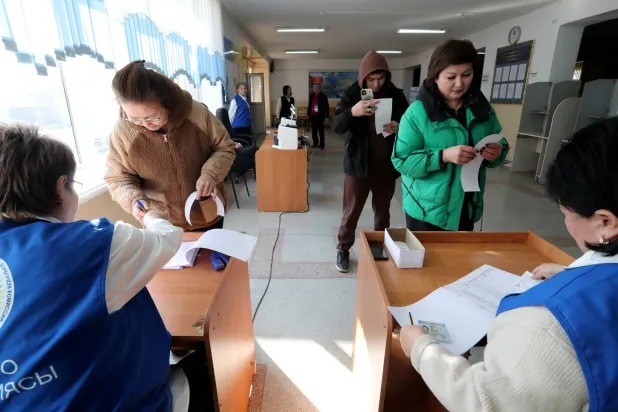 أعضاء اللجنة الانتخابية في مركز اقتراع خلال الانتخابات البرلمانية المبكرة في قرية كارا-زيغاتش قرب بيشكيك بقرغيزستان (إ.ب.أ)