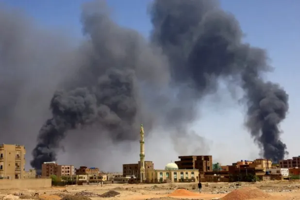 A man walks while smoke rises above buildings after aerial bombardment, during clashes between the paramilitary Rapid Support Forces and the army in Khartoum North, Sudan, May 1, 2023. REUTERS/Mohamed Nureldin Abdallah/File Photo